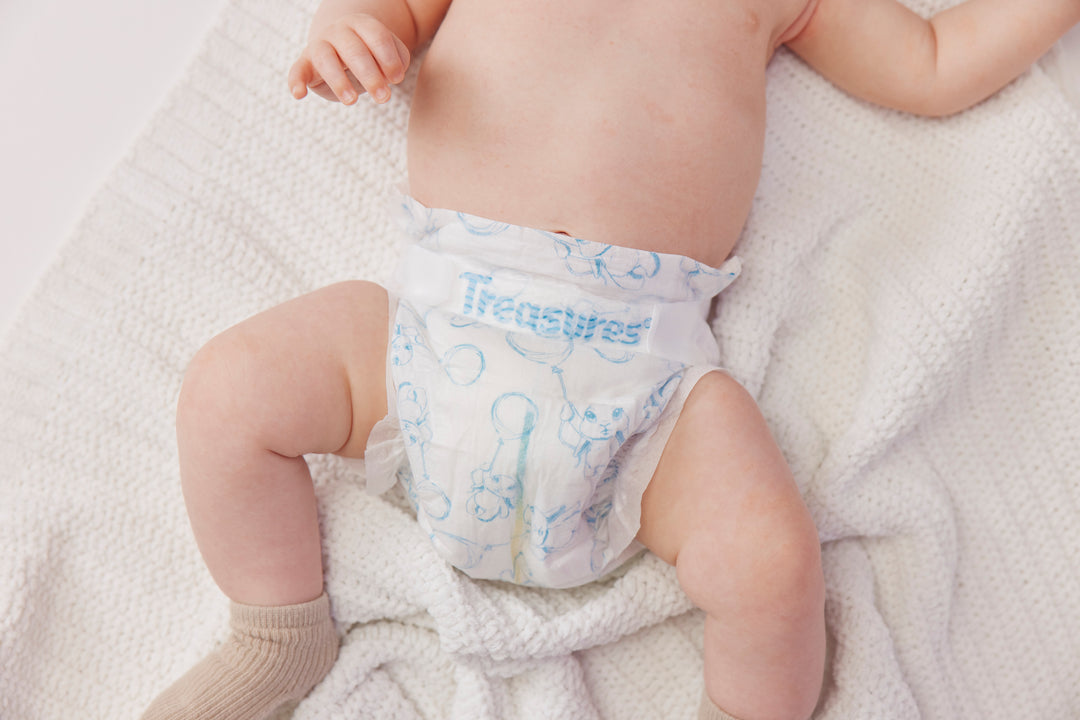 Close-up of a baby wearing a Treasures nappy on a cream knitted blanket